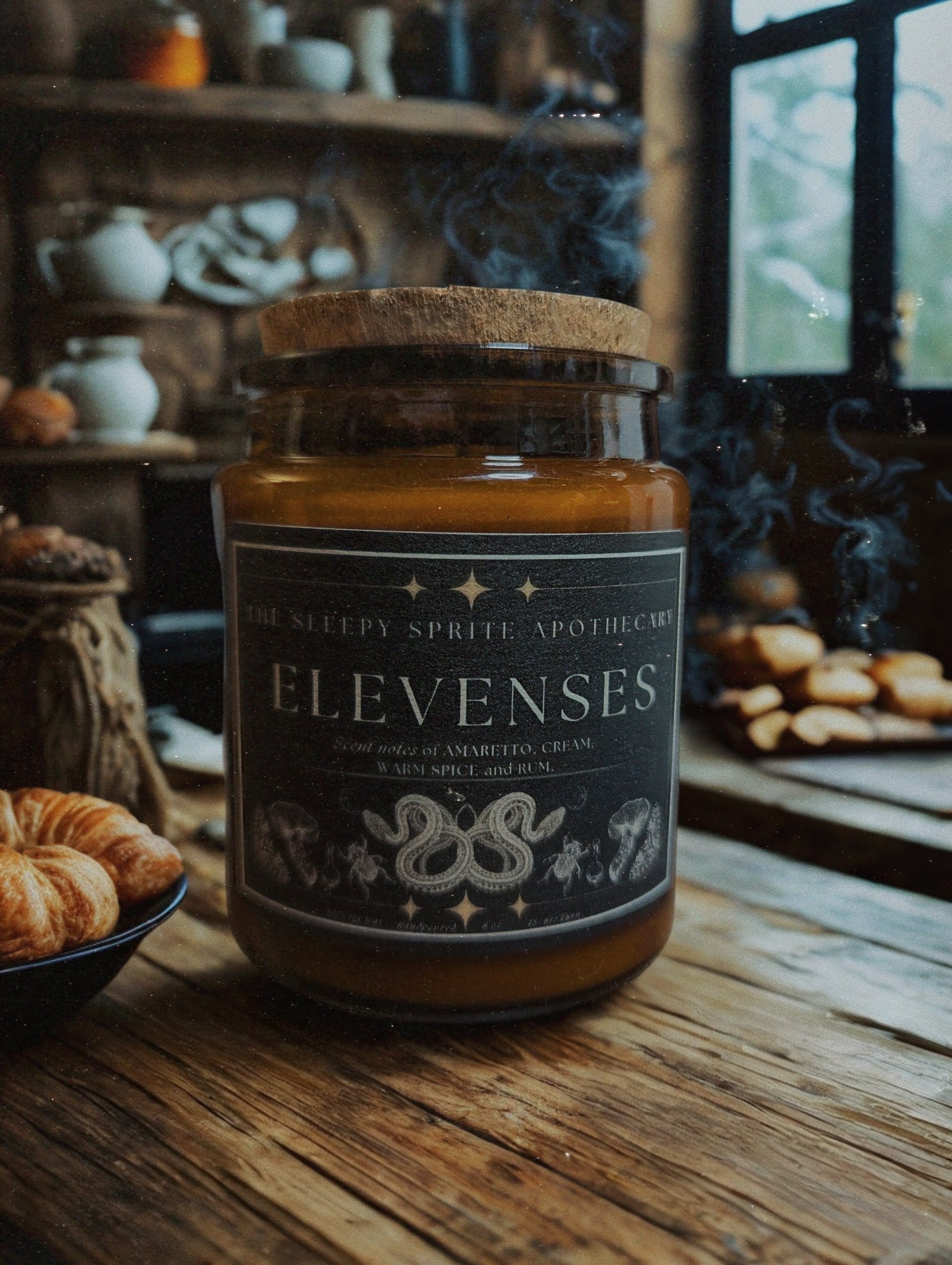 Jar of 'Elevenses' candle on a wooden table with a rustic background. Hobbit and Lord of the rings candle. Witchy dark cottagecore aesthetic.