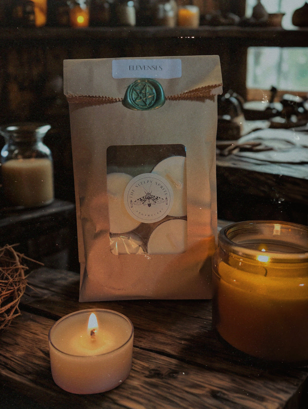 Packaged tealight candles  with a candle on a wooden surface. Elevenses hobbit and Lord of the rings candle. Witchy dark cottagecore aesthetic.