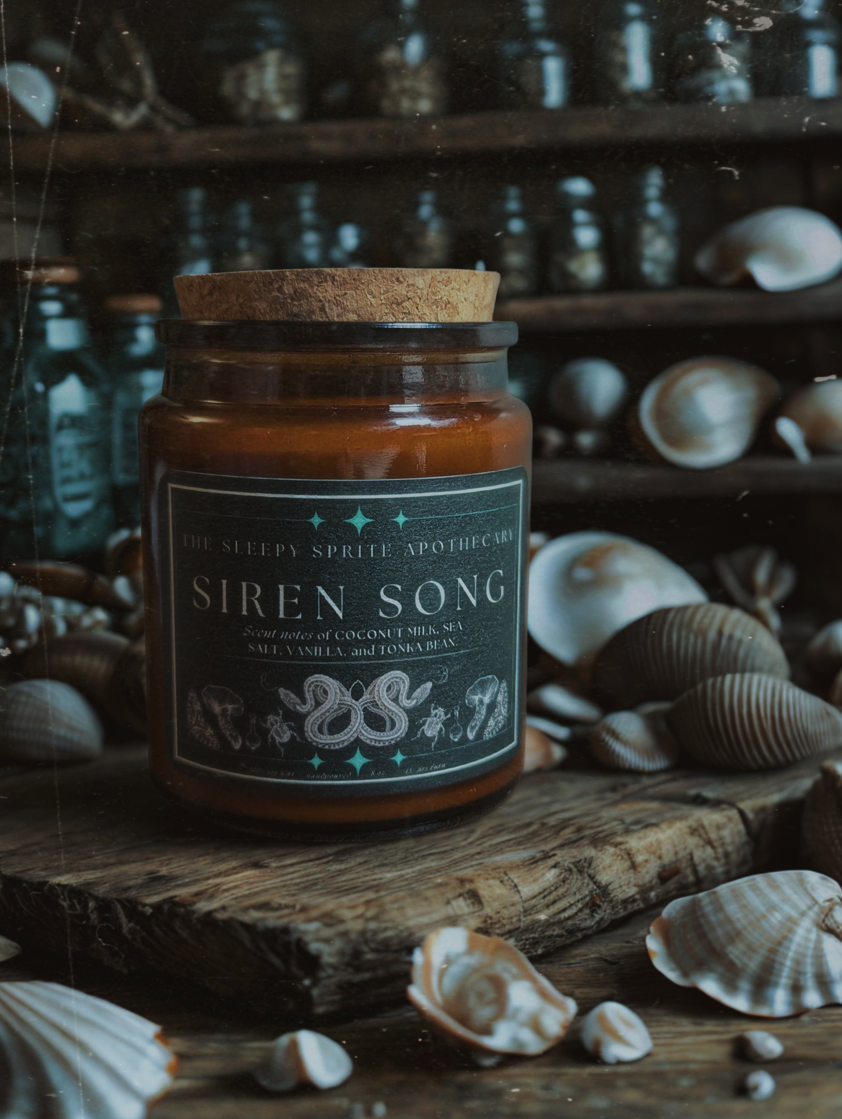 Candle jar labeled 'Siren Song' on a wooden surface with seashells in the background from The Sleepy Sprite Apothecary. Witchy dark cottagecore aesthetic.